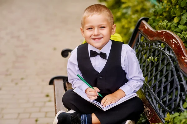 Красивый мальчик дошкольник с блокнотом в парке. дошкольное образование — стоковое фото