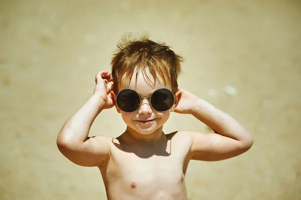 Счастливый мальчик на пляже, солнечные очки. Летний отдых — стоковое фото