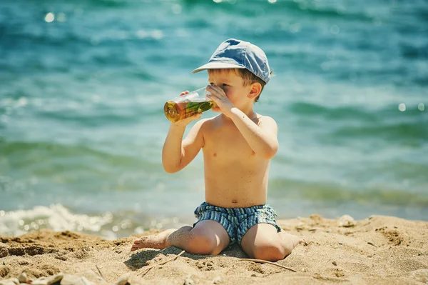 Niño pequeño en la playa con un vaso de bebida refrescante casera  . —  Fotos de Stock