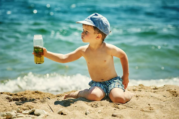 Mały chłopak na plaży z kieliszkiem domowego napoju orzeźwiającego . — Zdjęcie stockowe