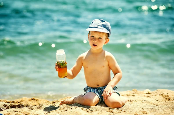 Μικρό αγόρι στην παραλία με ένα ποτήρι σπιτικό δροσιστικό ποτό . — Φωτογραφία Αρχείου