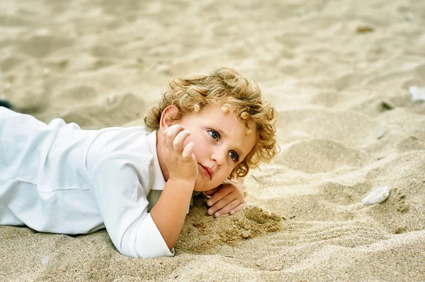 Στοχαστικό αγόρι ξαπλωμένο στην άμμο, κοντινό πορτρέτο . — Φωτογραφία Αρχείου