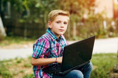 yakışıklı bir çocuk ile bir dizüstü bilgisayar açık havada oturma