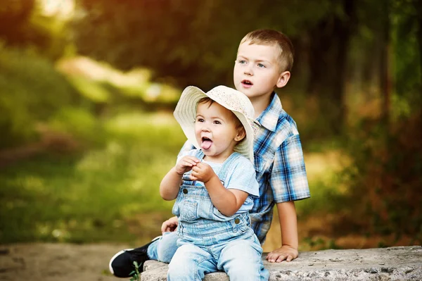 Funny little girl sitting with your brother in the Park — Stock Photo, Image