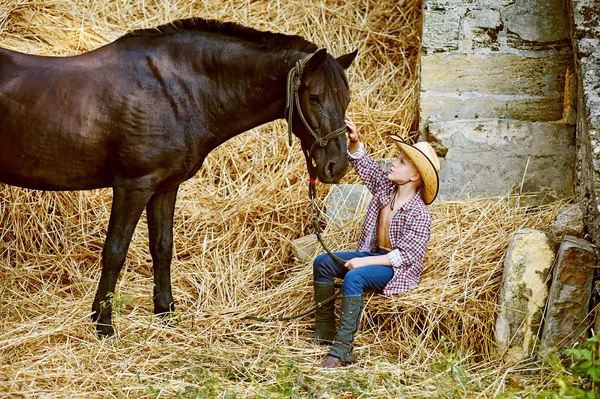 トレーニングの後の馬とポーズの少年。牧場 ロイヤリティフリーのストック画像