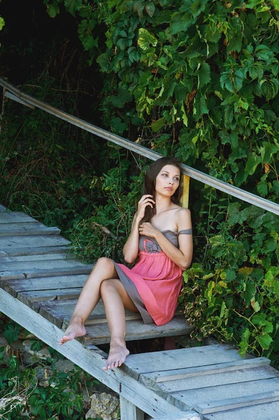 Junges schönes Mädchen sitzt abends auf Holztreppen — Stockfoto
