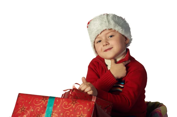 Bonito menino no chapéu vermelho do Papai Noel segurando uma caixa de presente — Fotografia de Stock