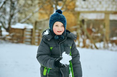 Kışın taze karda oynayan mutlu çocuk.