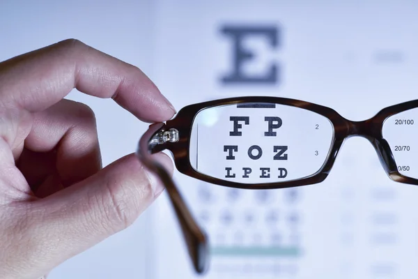 Mirando a través de anteojos en una carta de examen ocular — Foto de Stock