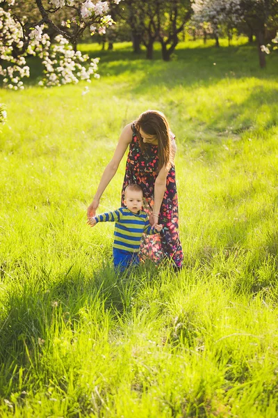 Junge Mutter hilft ihrem entzückenden kleinen Baby, erste Schritte zu machen — Stockfoto