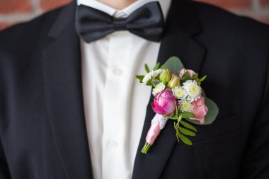 Siyah takım elbiseli adama tutturulmuş yaka çiçeği