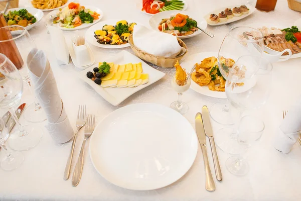 Mesa servida com diferentes alimentos e louças — Fotografia de Stock