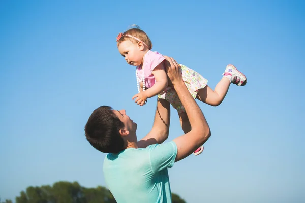 Little girl in pink dress on hands of her father — Stock Photo, Image