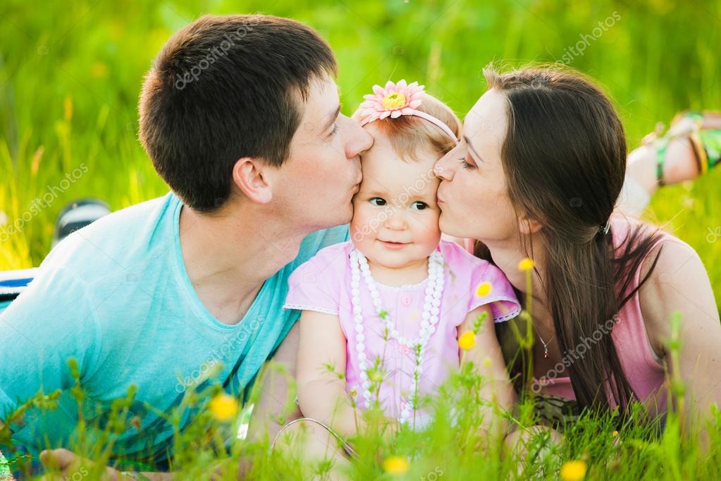 Mama und Papa küssen der kleinen Tochter die Wangen. Familienporträt