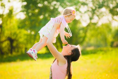 Mutlu anne ve kızı birlikte oynarken pembe giysiler giymiş 