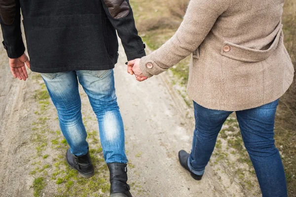 Joven hombre y mujer caminando por el camino del campo tomados de la mano —  Fotos de Stock