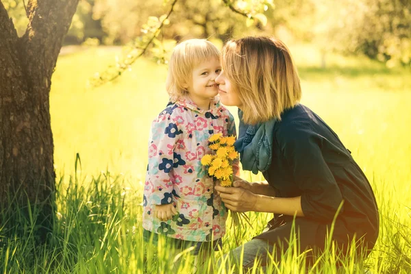 Kleines Mädchen und junge Mutter genießen Frühlingsfelder Löwenzahn — Stockfoto