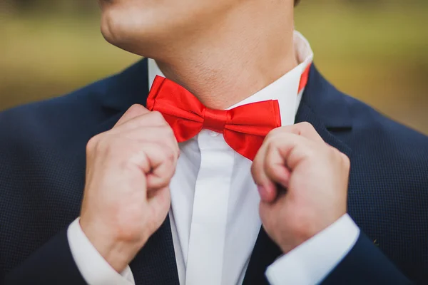 Primer plano de las manos del hombre corrigiendo la pajarita roja. El hombre usa azul s — Foto de Stock