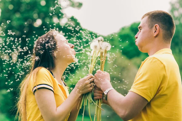 Pareja enamorada soplando alegres bolas de flores —  Fotos de Stock