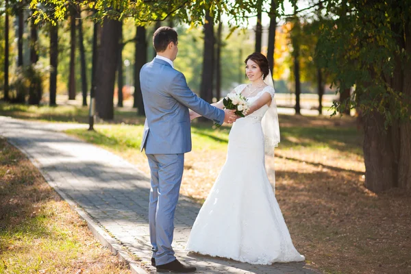 Happy bride, groom standing in green park — Stock Photo, Image