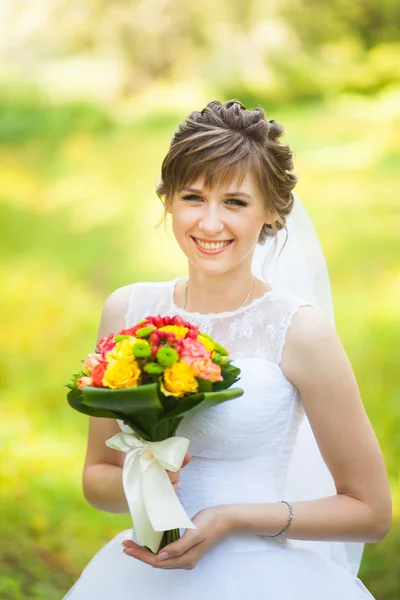 Прекрасная невеста в день свадьбы стоит в зеленом парке — стоковое фото