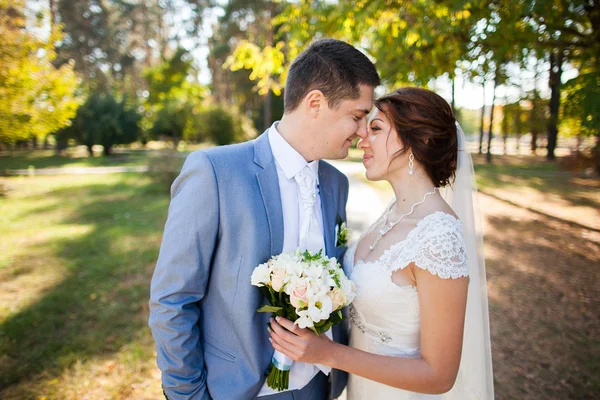 Lyckliga bruden, brudgummen står i grön park — Stockfoto