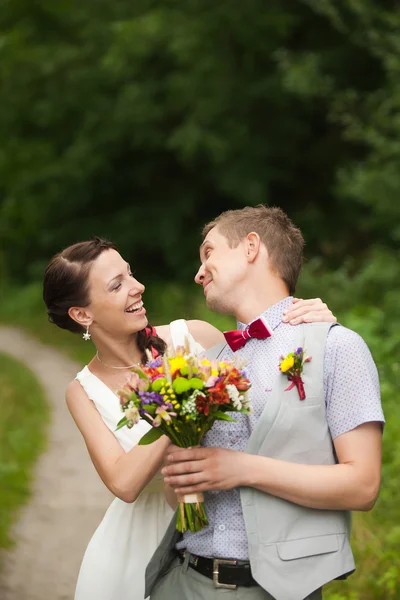 Happy bride, groom standing in green park — Stock Photo, Image