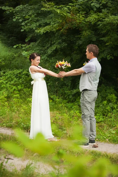Ευτυχισμένη νύφη, γαμπρός, στέκεται στο καταπράσινο πάρκο — Φωτογραφία Αρχείου