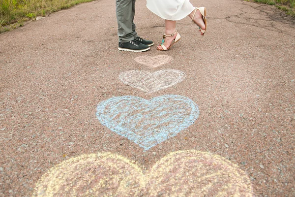 Símbolos del corazón con crayones en el suelo y dos personas enamoradas — Foto de Stock