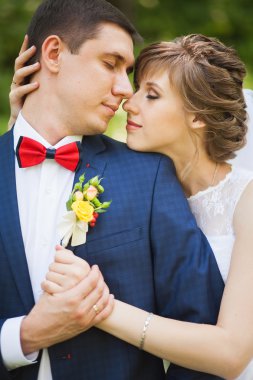 Mutlu gelin, yeşil park, ayakta damat öpüşme, gülüyor, gülüyor. yakın çekim