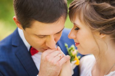 Mutlu gelin, yeşil park, ayakta damat öpüşme, gülüyor, gülüyor. yakın çekim