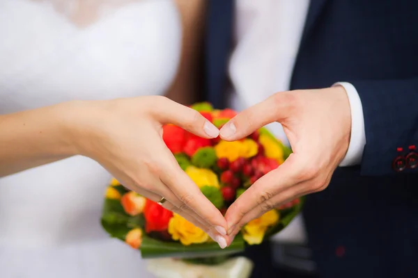 Felices recién casados, las manos muestran el corazón - símbolo del amor — Foto de Stock