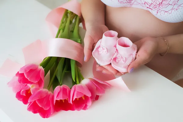 Mujer embarazada sosteniendo diminutos calcetines de niño rosa en las manos con amor —  Fotos de Stock