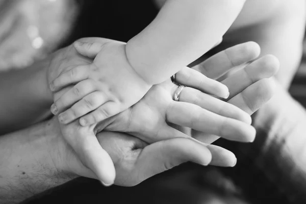 Closeup of baby's and parent's hands. black and white picture — Stock Photo, Image