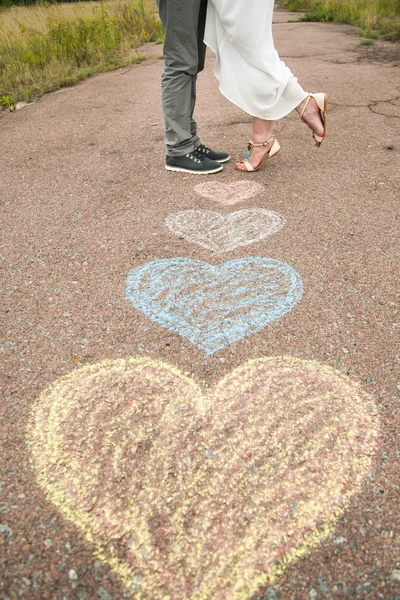 Heart symbols shaped with crayons on ground and two people in lo — Stock Photo, Image