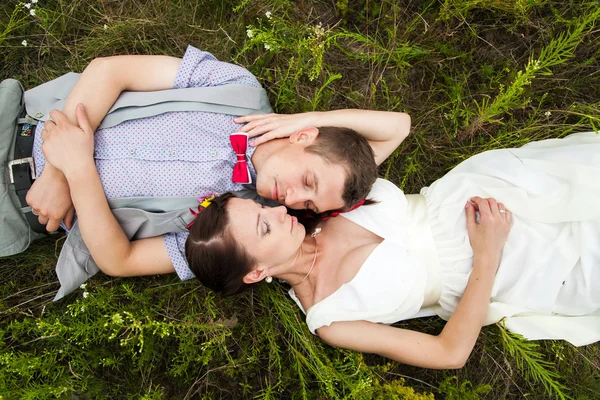 Casamento casal apaixonado deitado na grama verde no prado de verão — Fotografia de Stock
