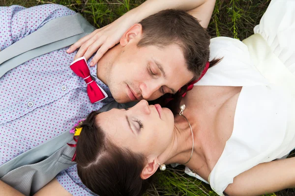 Casamento casal apaixonado deitado na grama verde no prado de verão — Fotografia de Stock