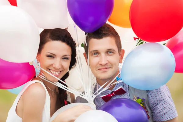 Hombre y mujer sosteniendo en las manos muchos globos de látex de colores — Foto de Stock