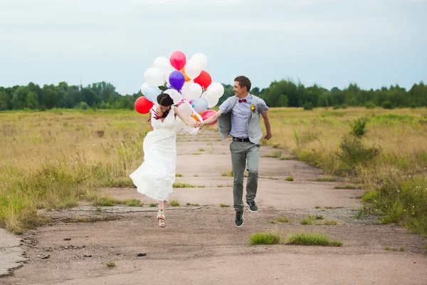 Man and woman holding in hands many colorful latex balloons — Stock Photo, Image