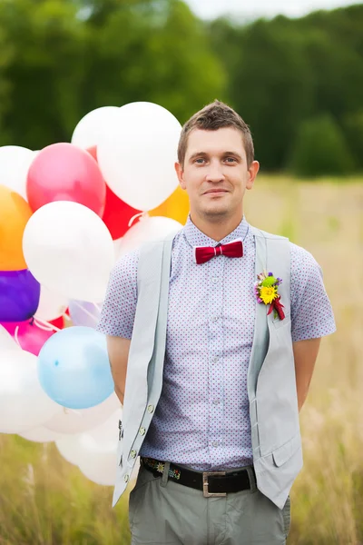 Feliz novio joven sosteniendo en las manos globos de látex de colores — Foto de Stock