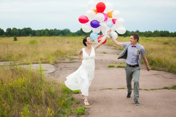 Man och kvinna håller i händer många färgstarka latex ballonger — Stockfoto