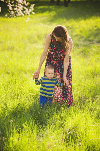 Baby läuft im grünen Park und hält die Hand der Mutter — Stockfoto