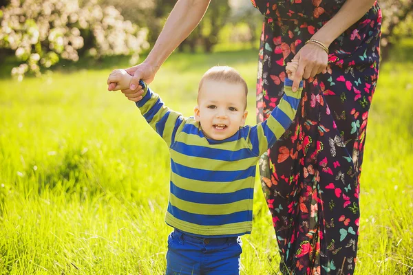 Baby walking in green park holding hands of mother — Stock Photo, Image