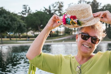 Parkta şapka takan 60 yaşındaki bir kadının yakın çekimi.