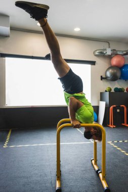 Spor salonundaki paralellerde çam kokulu spor yapan kaslı adam.