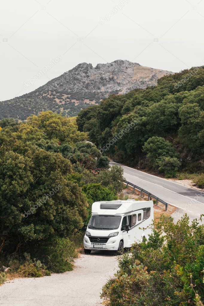 White motorhome traveling along a road through a forest