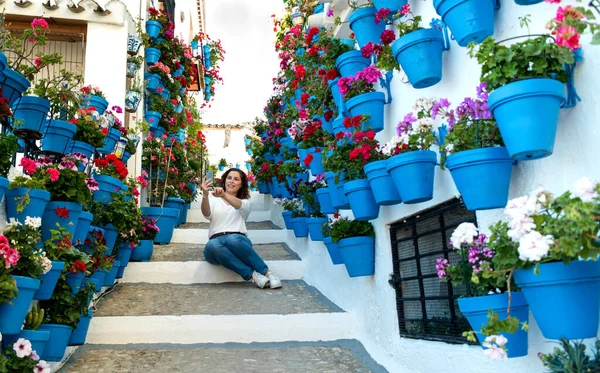 Schöne Frau macht ein Selfie auf einer Treppe voller Töpfe und Blumen in einem andalusischen Innenhof — Stockfoto