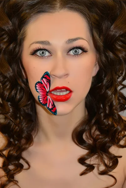 Schönes Mädchen mit einem Schmetterling auf den Lippen — Stockfoto