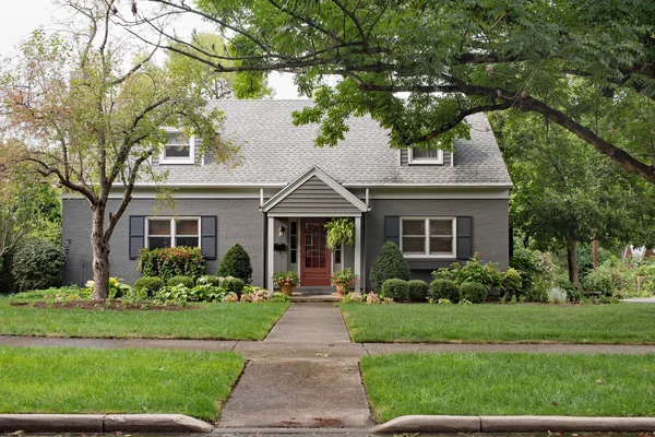 Grijze bakstenen Cape Cod-huis op bewolkte dag — Stockfoto