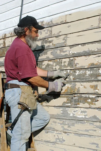 Hombre que rasca la pintura de la casa —  Fotos de Stock